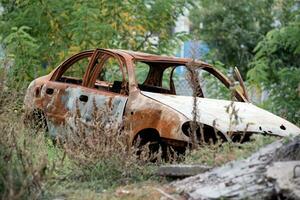 queimado Fora estourado acima carro contra a fundo do uma destruído casa guerra entre Rússia e Ucrânia foto
