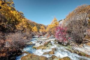 bela cachoeira na floresta de outono com céu azul foto