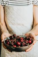 velha garçonete oferece e segura um cacho de cereja em um prato, frutas, vida saudável, boa alimentação, conceitos mediterrâneos, cópia espaço, imagem vertical foto