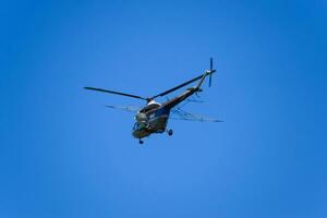 uma helicóptero do agrícola aviação é vôo dentro a azul céu. foto