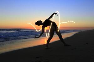 jovem dançarina habilidosa na praia durante o pôr do sol foto