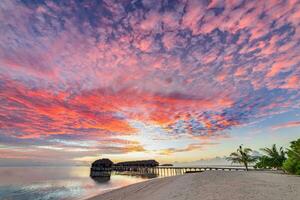 paisagem de praia incrível. bela vista do mar do pôr do sol das maldivas. horizonte colorido mar céu nuvens, sobre a água villa cais caminho. lagoa tranquila da ilha, fundo de viagens de turismo. férias exóticas foto