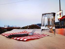 talheres, toalhas de mesa e copos em uma mesa de madeira de um restaurante ao ar livre na riviera da Ligúria foto