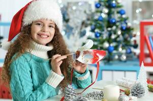 feliz menina dentro santa chapéu sentado com Natal presente foto