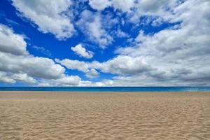 praia vazia fotografada com nuvens do céu e areia em maui havaí foto