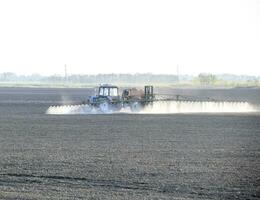 a trator pulverizado herbicidas em a campo. química dentro Agricu foto