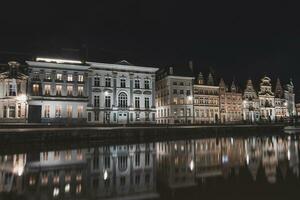 Visão em Sint-Michielsbrug dentro a Centro do Gent de a rio lei durante a noite. Bélgica a maioria famoso histórico Centro. Gent beira-mar durante meia noite foto