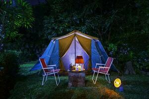 vintage cabine barraca, Antiguidade óleo lâmpada, retro cadeiras, grupo do acampamento tendas com ao ar livre fazer café instalações em de madeira mesas dentro uma floresta acampamento área dentro a floresta. foto