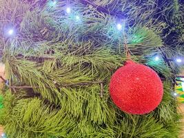 feliz Novo ano beleza casa interior com Natal árvore e guirlandas pequeno vermelho bolas. borrado luzes dourado bokeh verde folhas. alegre Natal fundo. foto