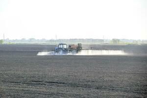 a trator pulverizado herbicidas em a campo. química dentro Agricu foto