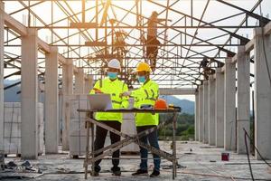 engenharia e supervisor trabalhando juntos no canteiro de obras e mascarados foto