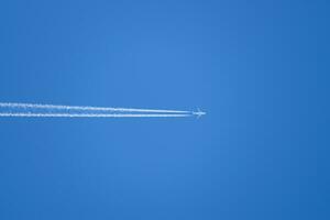 condensação trilha a partir de a avião dentro uma azul céu foto