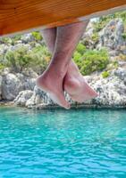 nu pés suspensão a partir de de madeira cais sobre mar água. feriado período de férias de a mar. foto