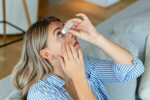 mulher usando olho derrubar, mulher caindo olho lubrificante para tratar seco olho ou alergia, doente mulher tratando globo ocular irritação ou inflamação mulher sofrimento a partir de irritado olho, ótico sintomas foto