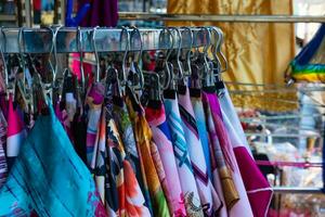 colorida lenços de cabeça ou covinhas suspensão em uma metal cabide dentro uma rua fazer compras foto