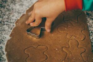 uma mãe e dela filho se empenhar dentro a delicioso tarefa do preparando Natal Pão de gengibre foto