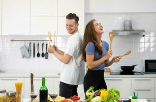 engraçado casal homem e mulher dançando dentro cozinha durante cozinhando às casa juntos foto