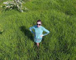 jovem menina dentro uma luz verde vestir em a gramado com verde grama. Visão do uma homem a partir de acima a partir de uma altura. foto