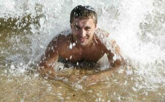 homem em a costa mentiras. a mar onda cobre a masculino. de praia foto