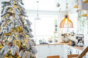 festivo Natal decoração dentro branco cozinha, moderno rústico interior com uma Nevado Natal árvore e fada luzes. Novo ano, Natal humor, acolhedor lar. a geral plano foto