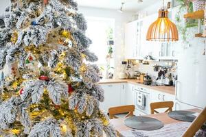 festivo Natal decoração dentro branco cozinha, moderno rústico interior com uma Nevado Natal árvore e fada luzes. Novo ano, Natal humor, acolhedor lar. a geral plano foto