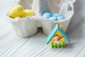 uma grupo do amarelo e azul ovos dentro ovo caixa. perto a casa com uma pássaro. a conceito do a abandonado casa do Ucrânia para a Páscoa feriado. foto
