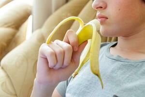 retrato do uma Adolescência Garoto comendo uma banana. foto do uma pessoal boca e lábios com uma banana. fresco fruta. saudável alimentos para crianças