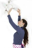 bonita mulher montar uma Novo luz lâmpada dentro a tomada foto