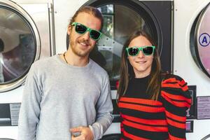 jovem amoroso casal vestindo verde oculos de sol dentro uma público lavanderia foto