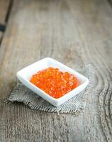 tigela de caviar vermelho na mesa de madeira foto