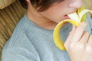 retrato do uma Adolescência Garoto comendo uma banana. foto do uma pessoal boca e lábios com uma banana. fresco fruta. saudável alimentos para crianças