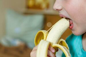 retrato do uma pequeno menina comendo uma banana. a conceito do saudável Comida. uma fresco rápido lanche foto