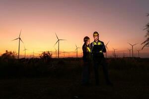 engenheiros trabalhando em vento turbinas Fazenda às pôr do sol, vento turbinas estão alternativo energia fonte. foto