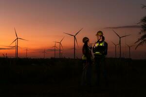 engenheiros trabalhando em vento turbinas Fazenda às pôr do sol, vento turbinas estão alternativo energia fonte. foto