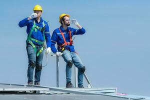 ambos do técnico reparação solar painéis descansar dentro a escaldante Sol em uma fábrica cobertura coberto com solar painéis para receber solar energia. foto