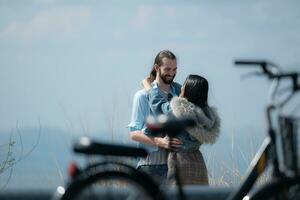jovem casal dentro amor em a topo do a montanha com bicicleta primeiro plano foto