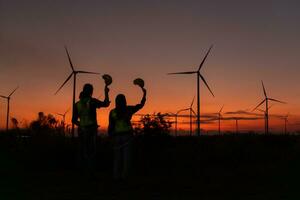 engenheiros trabalhando em vento turbinas Fazenda às pôr do sol, vento turbinas estão alternativo energia fonte. foto