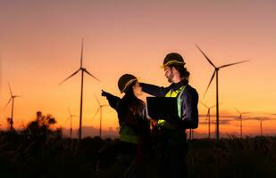 engenheiros trabalhando em vento turbinas Fazenda às pôr do sol, vento turbinas estão alternativo energia fonte. foto