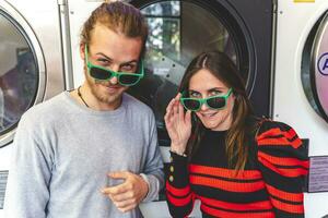 jovem amoroso casal vestindo verde oculos de sol dentro uma público lavanderia foto