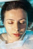 retrato do jovem menina dentro roupa de banho flutuando em azul água do natação piscina dentro luz solar foto