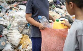 pobre crianças em a lixo despejo e selecionando plástico desperdício para vender, crianças não dentro escola, pobreza. foto