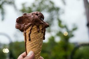 Derretendo chocolate waffle cone gelo creme dentro uma mão foto