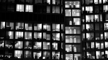 padronizar do escritório edifícios janelas iluminado às noite. vidro arquitetura , corporativo construção às noite - o negócio conceito. Preto e branco. foto