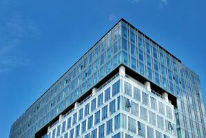 vidro construção com transparente fachada do a construção e azul céu. estrutural vidro parede refletindo azul céu. foto