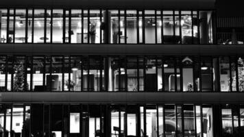 padronizar do escritório edifícios janelas iluminado às noite. vidro arquitetura , corporativo construção às noite - o negócio conceito. Preto e branco. foto