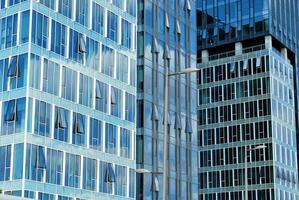 vidro construção com transparente fachada do a construção e azul céu. estrutural vidro parede refletindo azul céu. foto