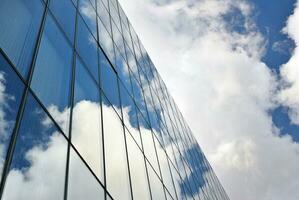 vidro construção com transparente fachada do a construção e azul céu. estrutural vidro parede refletindo azul céu. foto