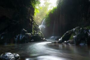Visita a charme do Indonésia com a lorong watu cachoeira, norte bengkulu. uma limitar beco forrado com pedra paredes, a manhã luz brilha em a cascata foto