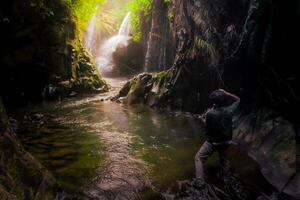 Visita a charme do Indonésia com a lorong watu cachoeira, norte bengkulu. uma limitar beco forrado com pedra paredes, a manhã luz brilha em a cascata foto