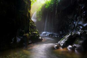 Visita a charme do Indonésia com a lorong watu cachoeira, norte bengkulu. uma limitar beco forrado com pedra paredes, a manhã luz brilha em a cascata foto